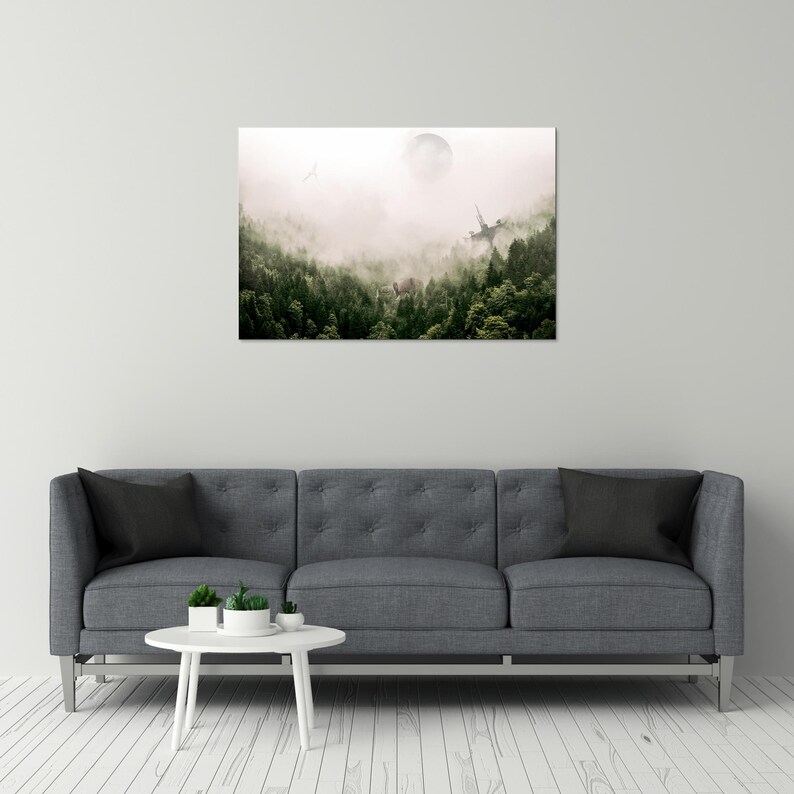 May include: A rectangular wall art print depicting a dense forest landscape shrouded in thick white fog. A pale, circular moon hangs in the upper center sky above the dark green pine trees, with a faint silhouette of a structure visible.