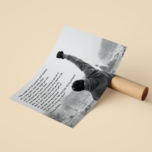 May include: Black and white poster featuring a motivational quote from Rocky Balboa. The image shows a person with their arm raised in a triumphant pose. The quote reads, "The world ain't all sunshine and rainbows." The poster is rolled up in a brown tube.
