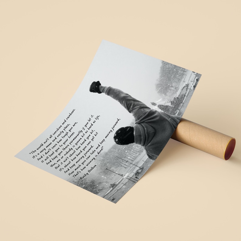 May include: Black and white poster featuring a motivational quote from Rocky Balboa. The image shows a person with their arm raised in a triumphant pose. The quote reads, "The world ain't all sunshine and rainbows." The poster is rolled up in a brown tube.