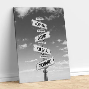 May include: A black and white wall art print featuring a vertical street sign post with four rectangular signs. The signs display the names SOPHIA, DAVID, OLIVIA, and RICHARD, each accompanied by a date: 28.10.2023, 25.12.2005, 22.05.1999, and 08.09.1993.