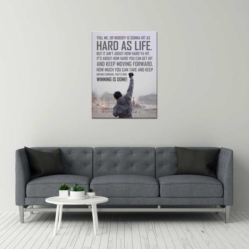 May include: A rectangular wall art print featuring a person in a grey hooded sweatshirt standing with one arm raised in a snowy outdoor setting. The text reads: YOU, ME, OR NOBODY IS GONNA HIT AS HARD AS LIFE. BUT IT AIN'T ABOUT HOW HARD YA HIT.