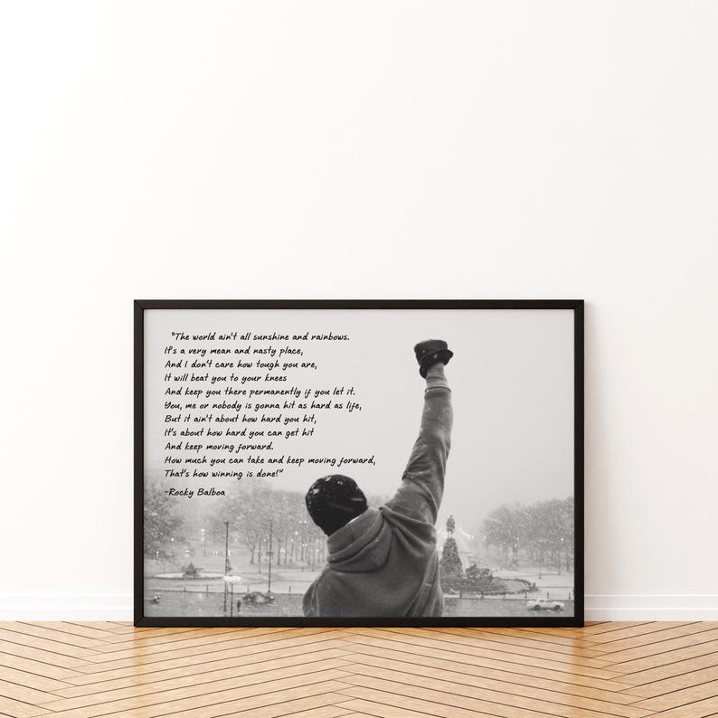 May include: Black and white framed print featuring a motivational quote from Rocky Balboa. The image shows a person with their fist raised in the air, with a snowy outdoor scene in the background. The quote is written in a script font.