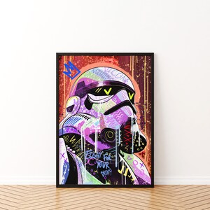 May include: A framed art print featuring a stylized Stormtrooper helmet with graffiti-style artwork. The helmet is rendered in vibrant colors including purple, green, and yellow, with the words "FIGHT FOR YOUR DREAMS".