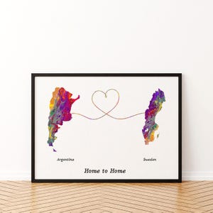 May include: A framed wall art print featuring a colorful, marbled map of Argentina on the left and Sweden on the right. A thin, continuous line connects the two countries, forming a heart shape in the center. The text reads Argentina, Sweden, and Home to Home.