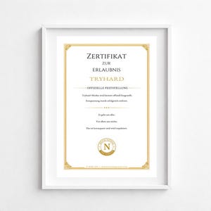 May include: A framed certificate with gold detailing and black text. The certificate reads "ZERTIFIKAT ZUR ERLAUBNIS TRYHARD" and includes additional text in German. The frame is white.