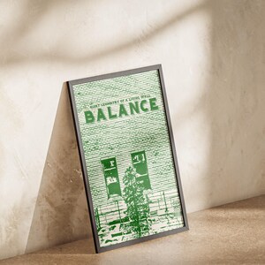 May include: A framed art print featuring a green and white illustration of a building facade with the word "BALANCE" in large green letters. The text "QUIET GEOMETRY OF A LIVING WALL" is above the word "BALANCE". The print is in a black frame.