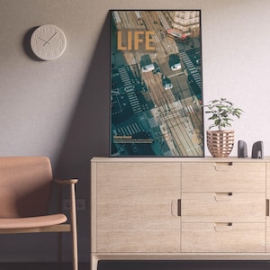 May include: A framed poster with the word "LIFE" in gold, showing an aerial city view. It's on a light wood cabinet with a plant and speakers. A round clock is on the wall. The cabinet is 120 cm wide, and the poster is 60 cm high.