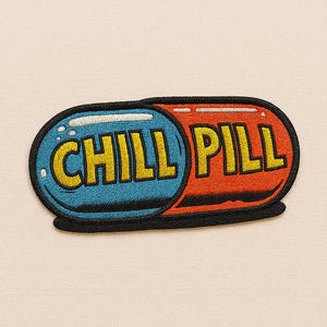 May include: Embroidered patch in the shape of a pill, with the words "CHILL PILL" in yellow block letters. The left side is blue, and the right side is red, with a black border. The background is a light beige colour.