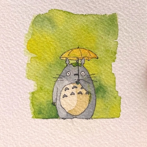 May include: Watercolour painting of a grey Totoro character holding a yellow umbrella. The character has a cream-coloured belly and is set against a green and yellow watercolour background. The artwork is on white paper.