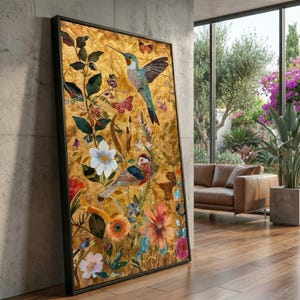 Op de afbeelding: Een ingelijst kunstwerk met een levendig bloemen- en fauna-ontwerp. Het toont een kolibrie en een kleurrijke vogel te midden van bloemen en vlinders, tegen een gouden achtergrond. Het zwarte frame voegt een moderne touch toe aan het op de natuur geïnspireerde stuk.