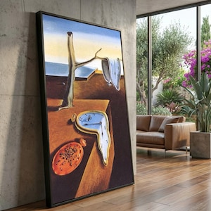 May include: Framed print of a surrealist artwork depicting melting clocks, a bare tree, and a barren landscape. The painting has a black frame and is displayed indoors, leaning against a concrete wall.