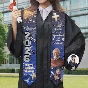May include: A personalized graduation sash with the text "Class of 2026 Amelia North Central College". The sash is blue with gold accents, a cross, and a photo. The text "I wanted to give up but I remembered who was watching" is also displayed.