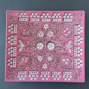 Op de afbeelding: Een rechthoekig roze decoratief dienblad met een ingewikkeld bloemmotief. Het ontwerp heeft witte en bruine bloempatronen, met kleine turquoise accenten. De lade heeft een opstaande rand en een glanzende afwerking, geschikt om te serveren of tentoon te stellen.