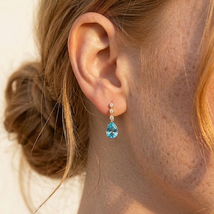 May include: A white ceramic mug with a black handle and the text "But First, Coffee" in a bold, black font. The mug is set against a blurred background, suggesting a cozy setting.
