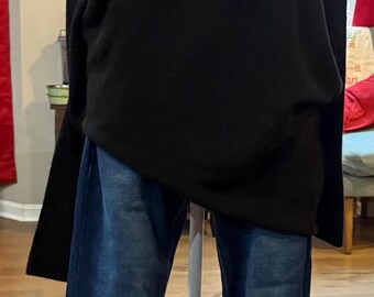 May include: A black sweater and blue jeans outfit displayed on a mannequin. The outfit includes a red plaid tie and jeans with floral embellishments at the ankles. The mannequin is on a white stand.