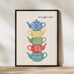 May include: A framed print showing a stack of teapots in various colours. The teapots are blue with white spots, yellow with flowers, green with stripes, red with hearts, and teal with a geometric pattern. The text "Time for Tea!" is at the top.