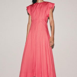 May include: A bright pink midi dress featuring a round neckline, structured cap sleeves, and a fitted bodice that transitions into a pleated, flared skirt. The garment is constructed with vertical seams and falls to a mid-calf length hemline.