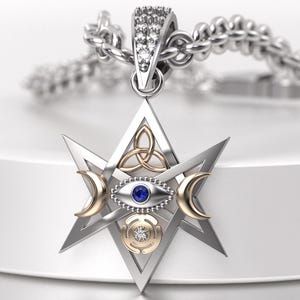 May include: A silver pendant necklace featuring a star-shaped design with a central eye motif and crescent moon accents. The pendant includes a blue gemstone and a gold-colored trinity knot. The necklace chain is also silver.