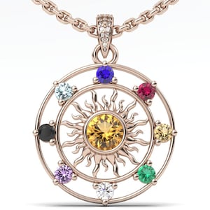 May include: Rose gold pendant necklace featuring a sunburst design with a central yellow gemstone and surrounding colorful gemstones. The pendant is suspended from a delicate chain. A celestial-themed jewelry piece.
