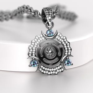 May include: A silver pendant necklace featuring a circular design with a sunburst center, adorned with small clear gemstones and three blue-green gemstones. The pendant hangs from a silver chain.