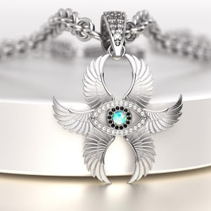 May include: A silver pendant necklace featuring a stylized eye design with wings. The eye has a central opal-like stone surrounded by black and clear stones. The pendant is suspended from a silver chain.