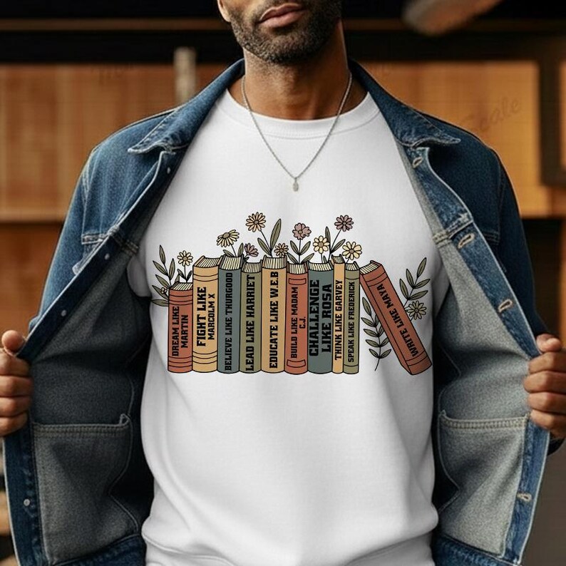 May include: White crew neck sweatshirt with a design of illustrated books and flowers. The book spines display motivational phrases such as "Dream Like Martin" and "Write Like Maya". A casual, comfortable style of sweatshirt.