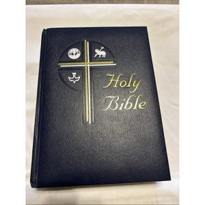 Könnte beinhalten: Eine dunkelblaue Bibel mit goldener Schrift. Das Cover zeigt ein goldenes Kreuzdesign mit religiösen Symbolen. Der Titel "Holy Bible" ist in eleganter goldener Schrift gehalten.