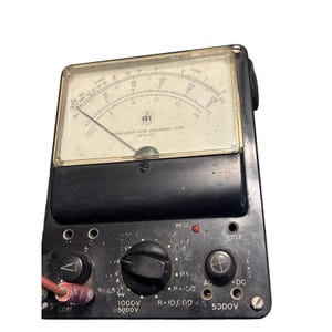 May include: Vintage black and gray analog multimeter with a clear display. The meter face has a needle and various scales for measuring voltage, current, and resistance. The device has several knobs, dials, and input terminals. The text "RUNO NEW YORK INDUSTRIES CORP MODEL PM-7" is visible.