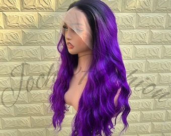 May include: A long, wavy wig with a gradient of colors, transitioning from black at the roots to vibrant purple. The wig is styled on a mannequin head, showcasing its length and texture. The hair appears soft and voluminous.