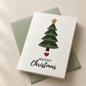 Puede incluir: Una tarjeta de felicitación blanca con un árbol de Navidad bordado en verde coronado por una estrella dorada, un pequeño corazón rojo bajo el tronco y el texto impreso en negro Merry Christmas, sobre un sobre de color verde salvia.