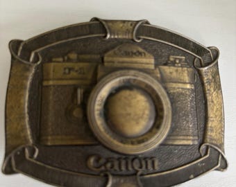 Vintage, collectible brass belt buckle featuring the Canon F-1 camera, manufactured by Lewis Buckles in the 1970s