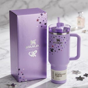 Puede incluir: Un vaso Stanley Quencher H2.0 lavanda con asa y caja de regalo a juego. Tanto el vaso como la caja presentan un dise&ntilde;o de estrellas y el logotipo de Stanley. El vaso tiene una pajita y una etiqueta que dice "All-Day Hydration".