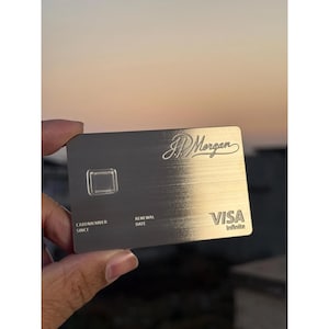 Op de afbeelding: Een zilveren Visa Infinite creditcard met het JP Morgan logo. De kaart heeft een geborstelde metalen afwerking en toont het Visa logo en de woorden "Cardmember Since" en "Renewal Date".