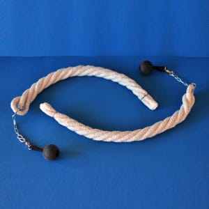 May include: A white rope flow toy with two black ball weights attached by chains. The rope is thick and twisted, and the background is a solid blue.