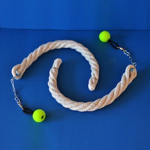 May include: A white rope toy with a spiral design, featuring two neon green balls attached by black cords and silver chains. The toy is set against a solid blue background, highlighting its playful design.