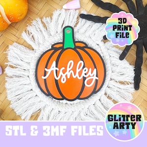 May include: A 3D printed pumpkin ornament featuring the name Ashley in white script lettering. The pumpkin is orange with a green stem and a black outline. The ornament includes a hole at the top for hanging and is labeled 3D Print File.
