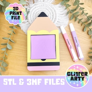 Op de afbeelding: Een potloodvormige notitieblokhouder met een lichtgeel en perzikontwerp, met een vierkant van paarse plaknotities. Twee roze en paarse markeerstiften en een regenboogsticker zijn ook zichtbaar. De tekst "3D PRINT FILE" staat op de sticker.