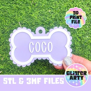 May include: A light purple bone-shaped pet tag with a scalloped edge and a white border. The name COCO is embossed in white letters in the center. A small circular hole is at the top for attachment. Includes text 3D PRINT FILE and STL & 3MF FILES.