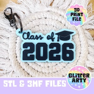 May include: A light blue keychain with the text "Class of 2026" and a graduation cap. The keychain has a black metal clasp and ring. The background is a cream-colored macrame coaster. The image also includes the text "3D PRINT FILE" and "Glitter Arty".