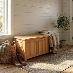 May include: A rectangular wooden storage bench with vertical slat detailing and a hinged lid. A textured beige knit throw blanket is draped over one side of the bench. The bench is crafted from light-toned wood with a natural grain finish.
