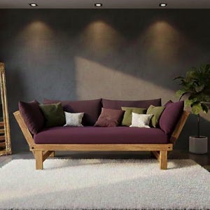 May include: A modern futon sofa with a wooden frame and a deep purple cushion. The sofa is adorned with various throw pillows in shades of green, purple, and white. The room features a large gold-framed mirror and a white shag rug.