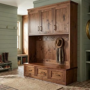 May include: A large, dark wood entryway storage unit with three upper cabinets, a bench with three drawers, and a section for hanging coats and hats. A hat and scarf hang from hooks. The unit is in a room with a light green wall.