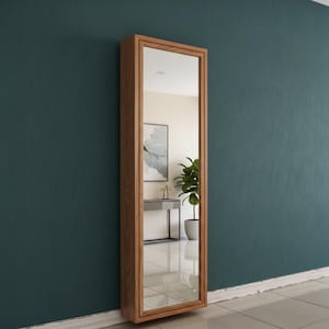 Può includere: Un lungo specchio rettangolare con cornice in legno, montato su una parete verde acqua. Lo specchio riflette una stanza con un dipinto, un tavolo e una pianta in vaso. La cornice ha una finitura in legno naturale.