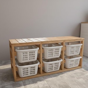 May include: A wooden laundry sorter with six white plastic baskets. The sorter is made of light-colored wood and has a rectangular shape. The baskets are arranged in two rows of three.