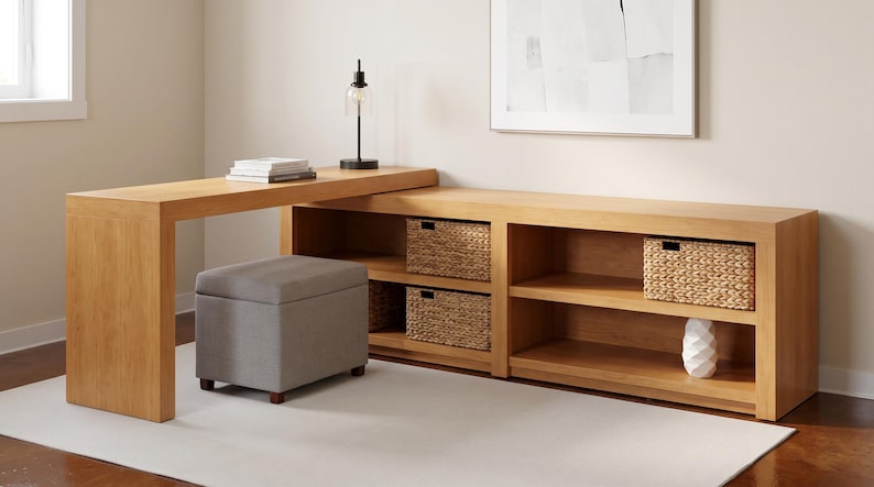 May include: A light wood desk with an attached bookcase and storage baskets. A gray upholstered ottoman sits in front of the desk. A lamp and books are on the desk. A white rug is on the floor.