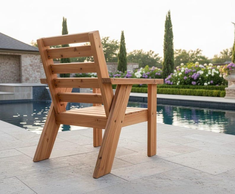 以下が含まれることがあります： 背もたれとアームレストが付いた木製のアウトドアチェア。椅子は明るい色の木材で作られており、プールの近くに配置されています。椅子のデザインはシンプルで頑丈で、パティオや庭に適しています。