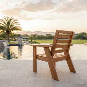 以下が含まれることがあります： スラットバックとアームレストを備えた木製のアウトドアチェア。椅子は明るい色の木材で作られており、石のパティオに配置されています。背景にはプール、ヤシの木、美しい景色があります。
