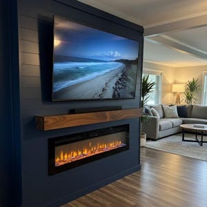 May include: A modern navy blue wall unit featuring a large flat-screen television, a wooden shelf, and an electric fireplace with a realistic flame effect. The unit is set against a backdrop of a living room with a gray sectional sofa.