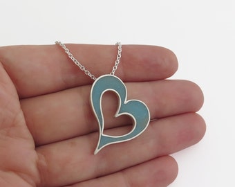 May include: A silver heart pendant necklace with a light blue enamel fill. The open heart design hangs from a delicate chain. The necklace is displayed against a white background.