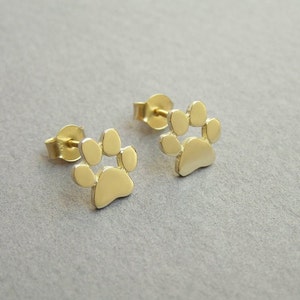 May include: A pair of gold-toned paw print stud earrings. The earrings are small and delicate, and they would make a great gift for any dog lover.